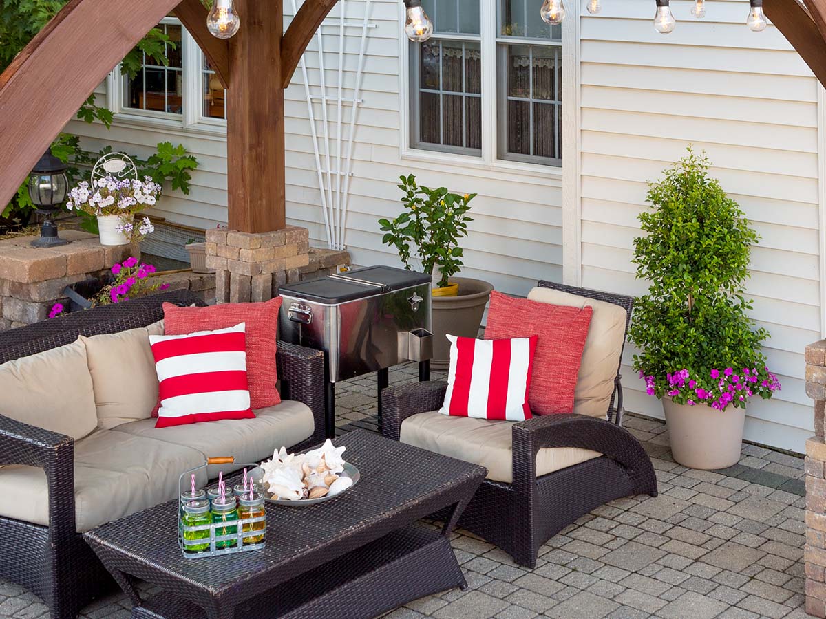 An outdoor patio with patio furniture, flower pots, and other items.